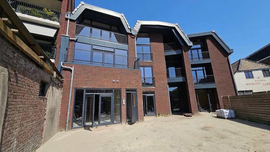Binnenterrein met de gevel op de hoek en een lage bakstenen muur ernaast