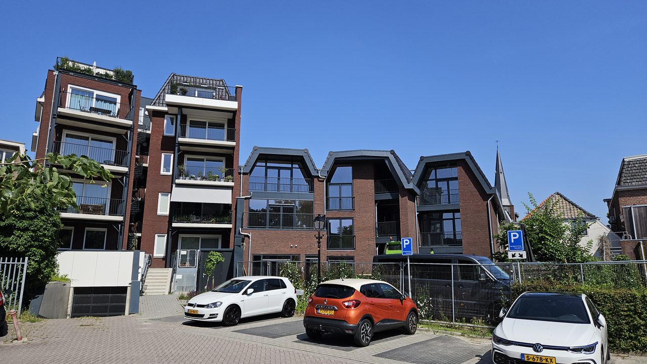 De nieuwbouw gezien vanaf het parkeerterrein, met de kerktoren rechts