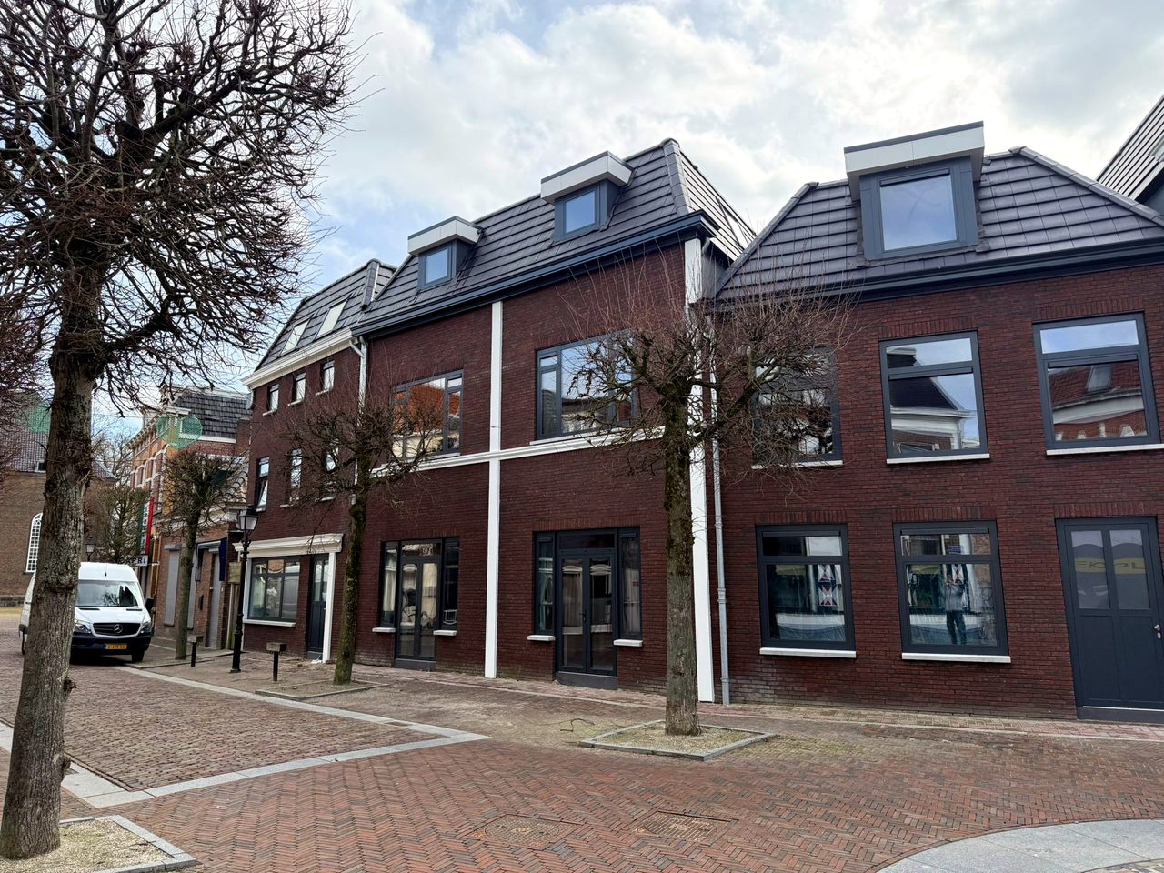 De straat met de gerestaureerde gevels, bij winters licht met kale bomen