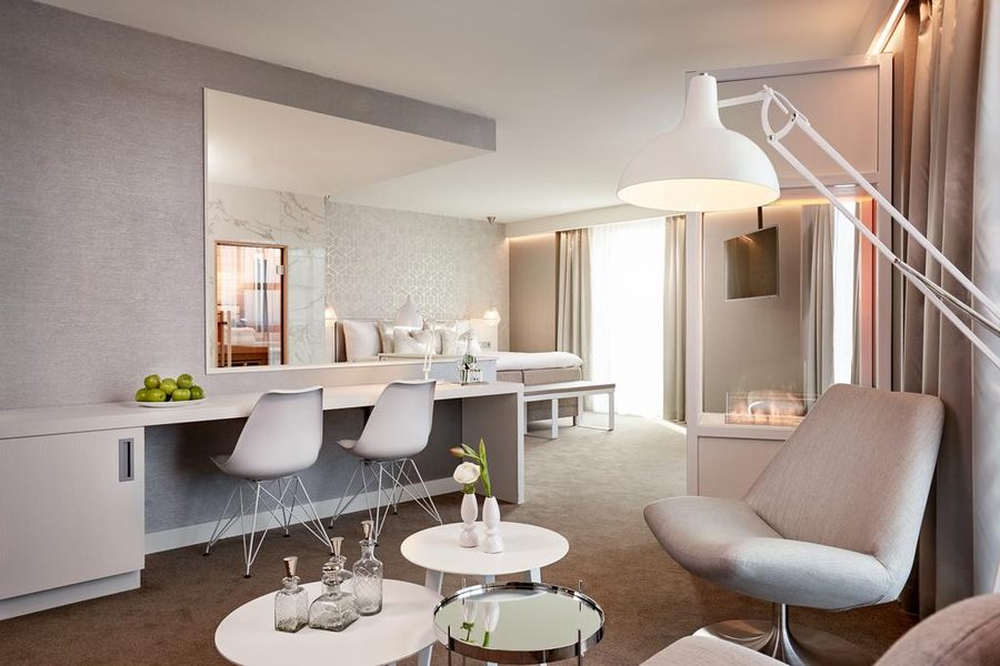 Hotelkamer in lichte tinten, met een zithoek en een bed achterin