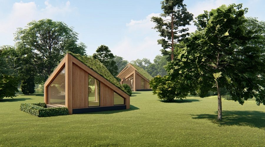 Impressie van twee houten paviljoens met begroeid dak op een open plek tussen de bomen