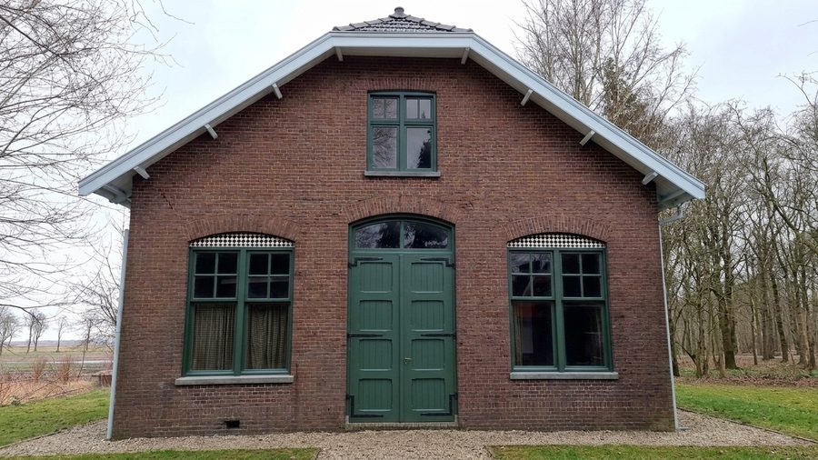 Kopgevel van de kazerne met boogramen in gemetselde speklagen en monumentgroen geschilderde kozijnen