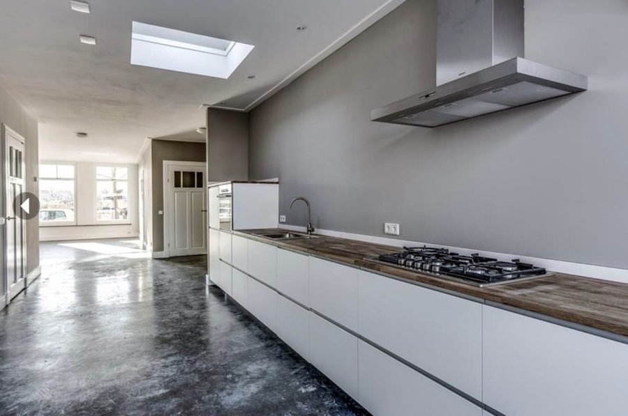 Keuken met witte kastenwand, houten blad en een doorlopende betonvloer