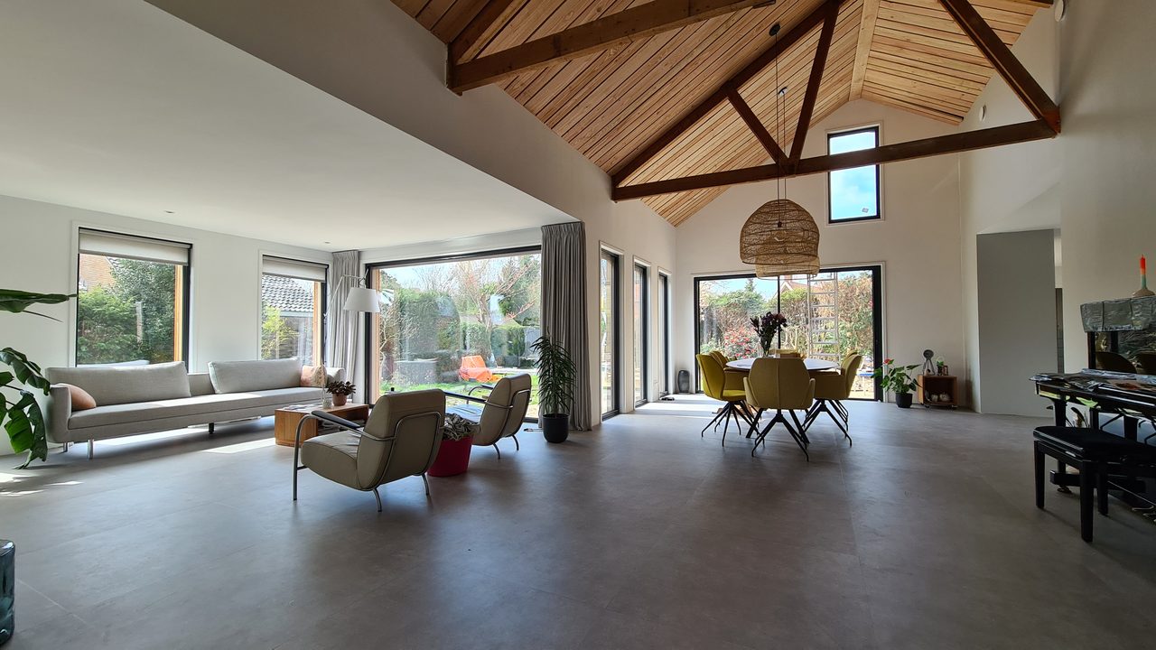 Woonruimte met zichtbare houten spanten onder een houten plafond