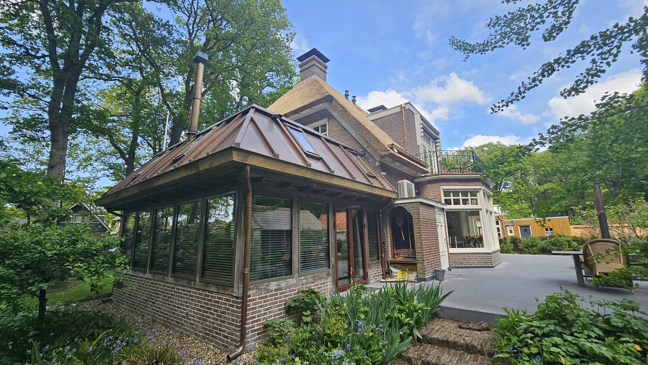 De serre gezien vanuit de tuin, tussen de beplanting door