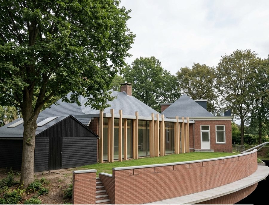 Hoekaanzicht van de aanbouw met de houten kolommen, met de schuur en het hoofdgebouw ernaast