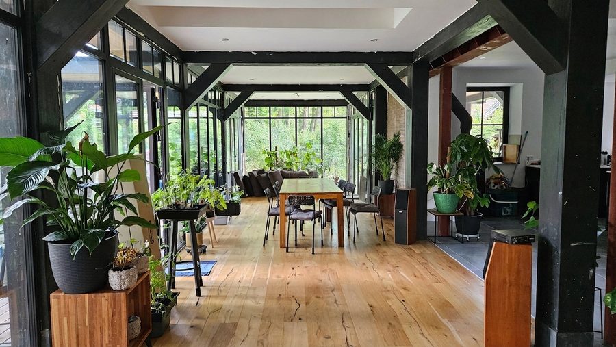 Doorkijk langs de houten kolommen- en liggerconstructie naar de eettafel en de tuin