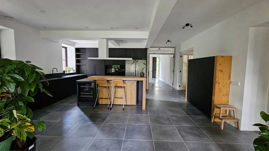 Open keuken met donkere kastenwand en een doorlopende tegelvloer