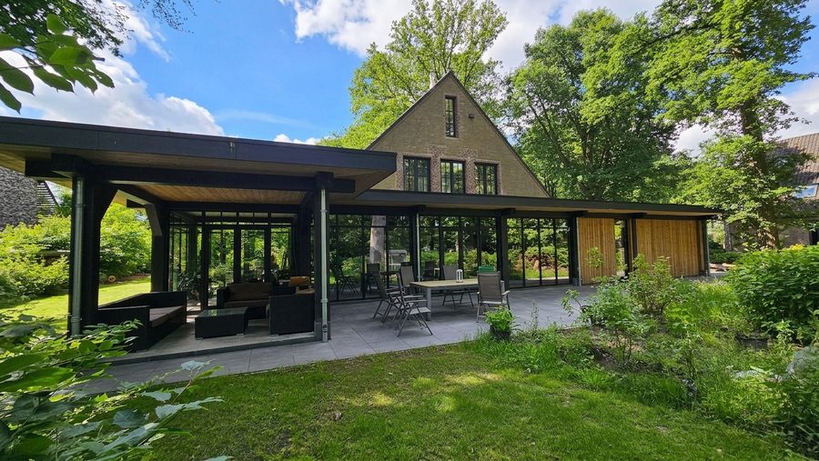 De veranda vanaf de zijkant, met de eettafel en de bakstenen kopgevel erachter